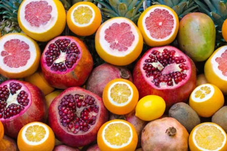 Eine Auswahl an Vitamin C-reichen Früchten (Grapefruit, Zitronen, Granatapfel etc.) liegen auf einem Tisch.