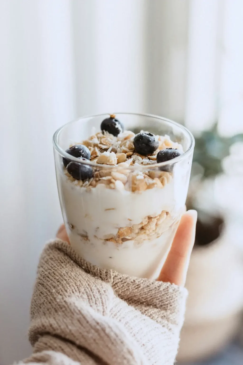 Frau hält gesunde, zuckerfreie Overnight Oats in der Hand.