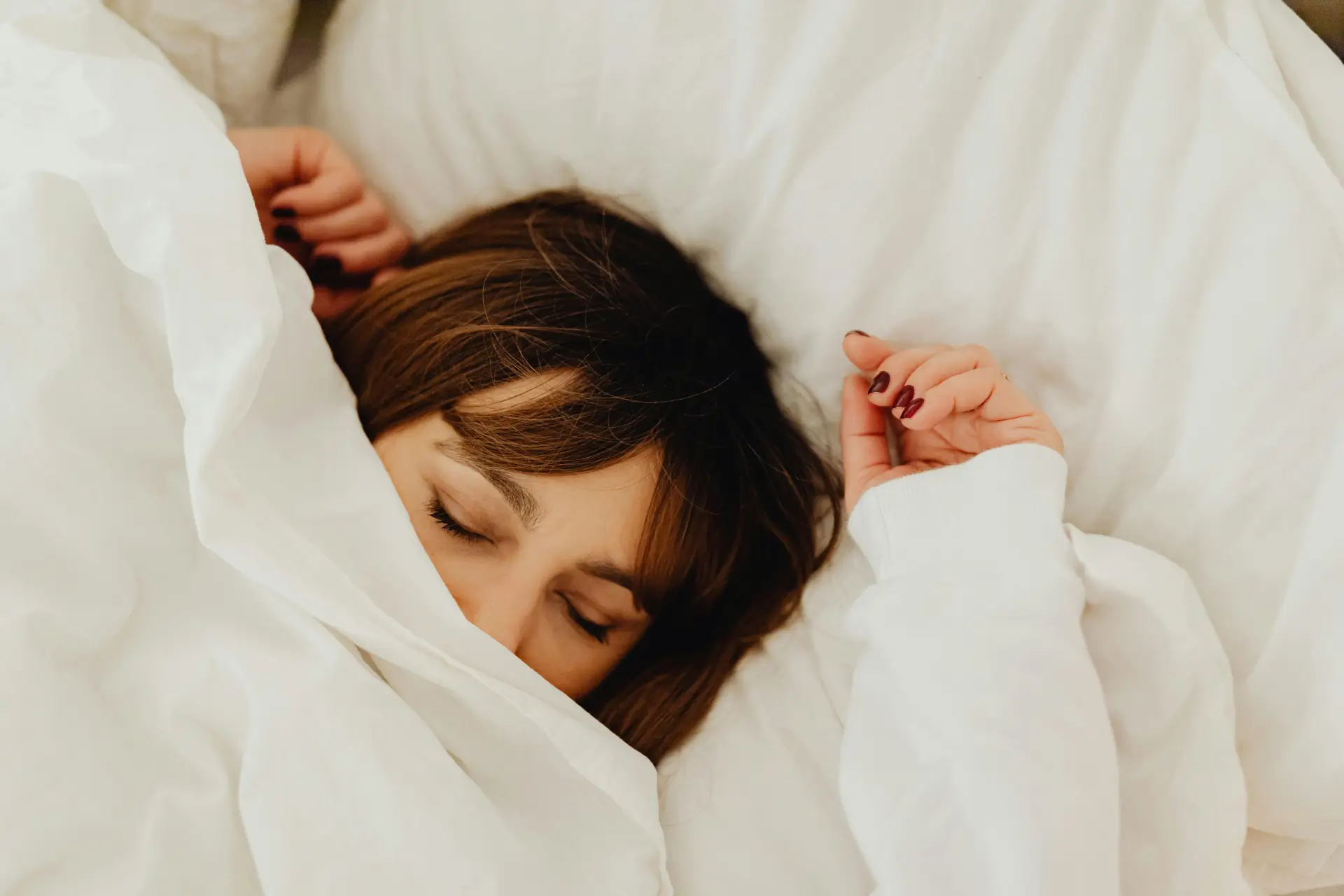 Junge Frau schläft tief, dick zugedeckt.