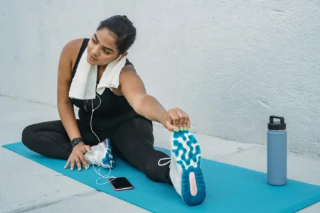 Junge Frau dehnt sich auf einer Yogamatte.