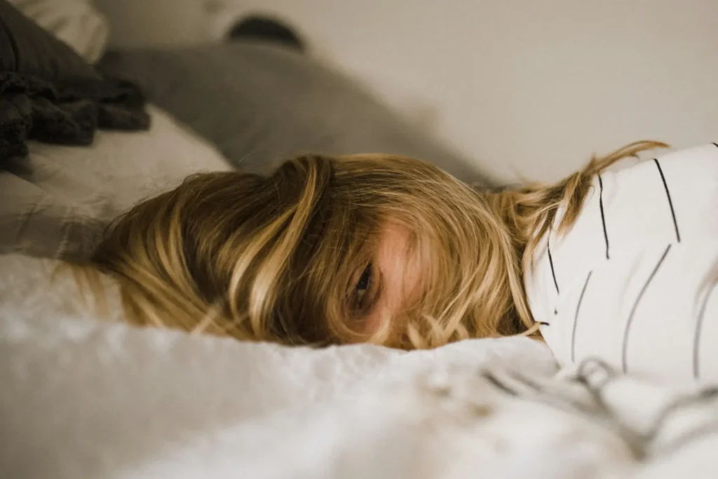 Junge Frau liegt erschöpft auf ihrem Bett aufgrund der Blutzucker-Achterbahn